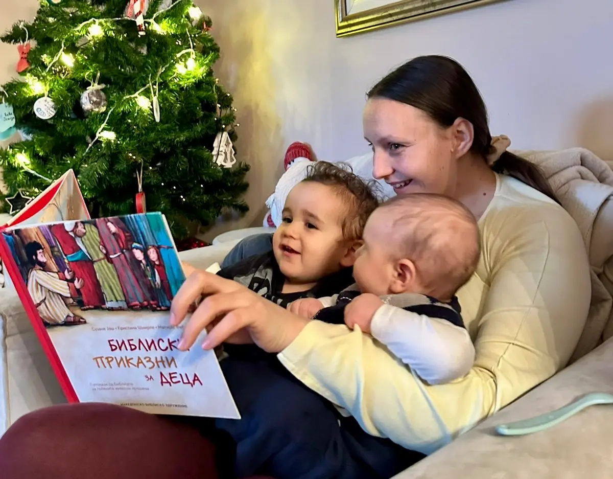 A mother reading a Bible storybook to her two young children