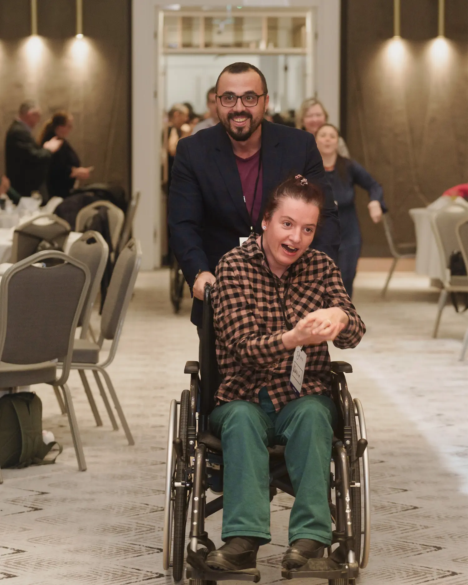 A volunteer pushing an honored guest in a wheelchair at Night to Shine